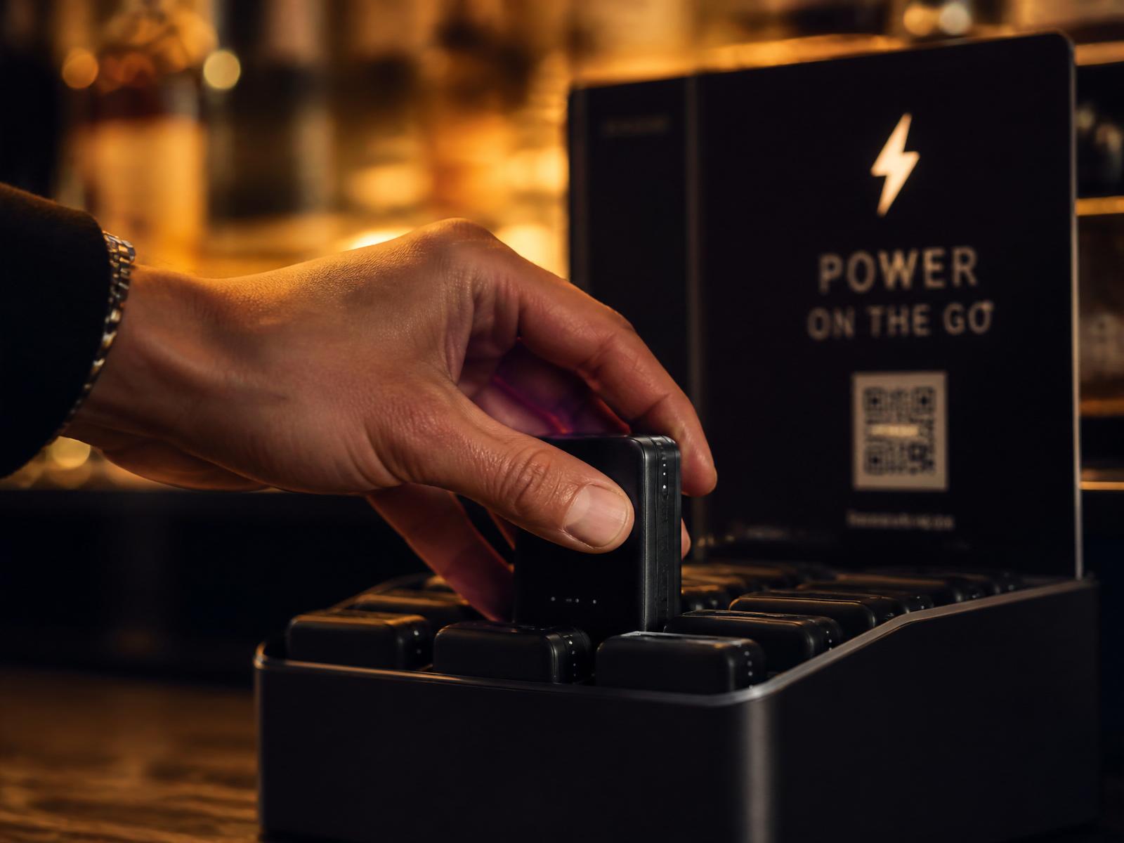 Une main récupérant une batterie externe Quickly d'une station